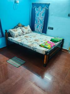 a small bed in a room with a blue wall at Sumathinandanakuteer in Pithāpuram +8 photos