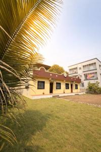 a yellow house with a palm tree in the foreground at The Calm Courtyard- Pune in Pune