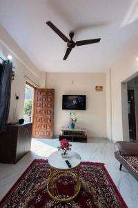 a living room with a ceiling fan and a table at The Calm Courtyard- Pune in Pune