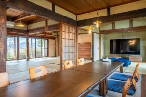 a large room with a table and chairs and a flat screen tv at Sauna Private Villa AO in Takashima