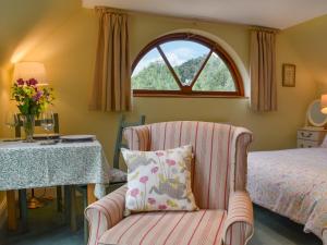 a bedroom with a bed and a chair and a window at Gwel An Lowarth in Lostwithiel