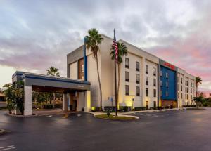 a large white building with palm trees in a parking lot at Hampton Inn & Suites Port St. Lucie in Port Saint Lucie