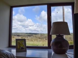 a lamp sitting on a table in front of a window at Meadow Cottage in Leek