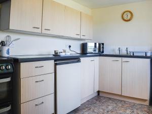 a kitchen with white cabinets and a microwave at Meadow Cottage in Leek