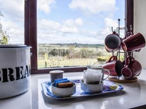 a table with a tray of coffee cups and a window at Meadow Cottage in Leek
