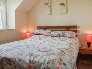 a bedroom with a bed with a floral bedspread and two lamps at Meadow Cottage in Leek +14 photos