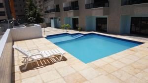 una gran piscina con 2 sillas y un sillón en Via Venneto Flat, en Fortaleza