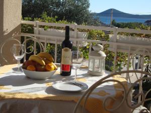 a table with a bottle of wine and a bowl of fruit at Adria Sun Apartments in Vodice