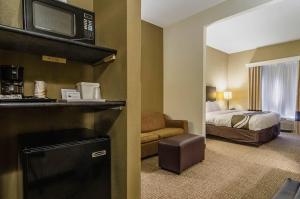 a hotel room with a bedroom with a bed and a television at Quality Suites Graham - Burlington South in Graham +22 photos