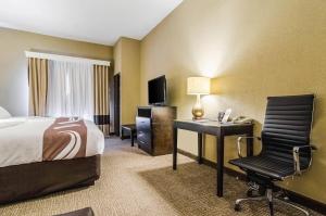 a hotel room with a bed and a desk and a television at Quality Suites Graham - Burlington South in Graham