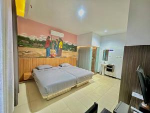 a bedroom with a bed and a painting on the wall at Ladja Hotel Sintang in Sintang