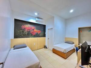 a bedroom with two beds and a painting on the wall at Ladja Hotel Sintang in Sintang