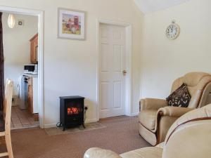 a living room with a couch and a stove at Stable Cottage in Leek