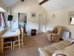a living room with a couch and a table and a stove at Stable Cottage in Leek