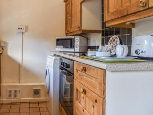 a kitchen with a stove and a microwave at Stable Cottage in Leek
