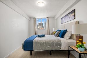 a bedroom with a bed with blue pillows and a window at 17th Ave Cozy Place in DT, short walk to Calgary Stampede in Calgary