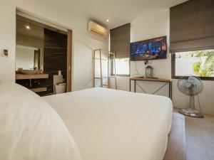 a bedroom with a white bed and a television at Calypso Villa Phuket - Naiyang Beach in Nai Yang Beach