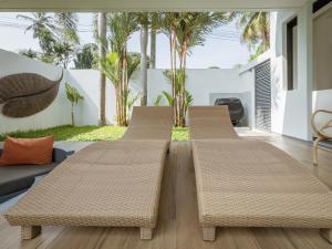 three rattan benches in a living room with palm trees at Calypso Villa Phuket - Naiyang Beach in Nai Yang Beach +63 photos