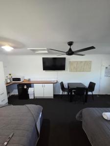 a room with a table and a ceiling fan at Agnes Palms Motel in Agnes Water