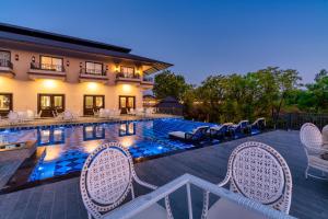 a swimming pool with chairs and a house at Amrutham Bagh Resort & Spa in Udaipur