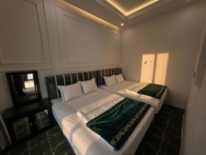 a bedroom with a large bed with white and green sheets at Altea House in Diyeng