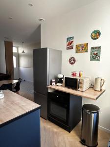 a kitchen with a counter with a microwave and a refrigerator at Au papillon des coteaux in Magenta +4 photos