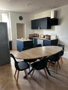 a kitchen with a wooden table and chairs at Au papillon des coteaux in Magenta