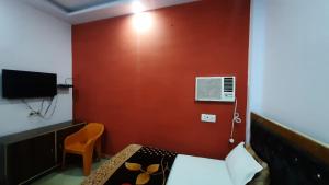 a bedroom with a red wall with a bed and a chair at Hotel Rajganga in Gonda