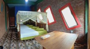a room with a bed and a table and windows at Terico resort in Belihuloya