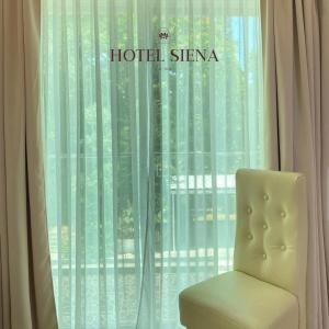 a white chair sitting in front of a window at Hotel Siena in Sampong