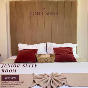 a bed with red pillows and a hotel sirmania sign at Hotel Siena in Sampong