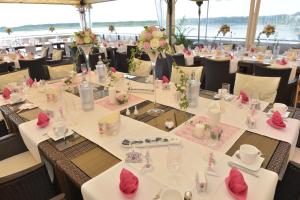 a dining room with tables and chairs with pink flowers at Seehotel Berlin-Rangsdorf in Rangsdorf +23 photos