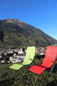 two green and red chairs sitting on top of a hill at Ostello del Castello Tirano in Tirano