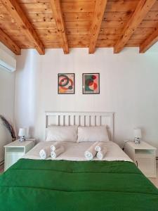 a bedroom with a bed with green sheets and wooden ceilings at Casa Vacanza Nì Rosa in Cefalù +46 photos