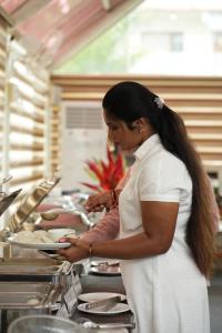 a woman standing in a kitchen preparing food at Advaya Luxury Resort, Sakleshpur in Sakleshpur