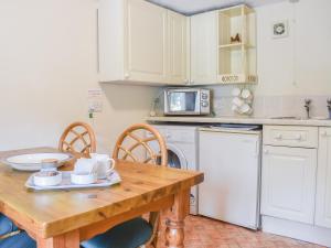 a kitchen with a wooden table with chairs and a sink at Swallow Cottage in Leek