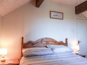 a bedroom with a bed with two lamps on tables at Swallow Cottage in Leek