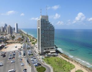 a tall building next to a beach with the ocean at Panoramic Sea View Luxury Suite in Netanya
