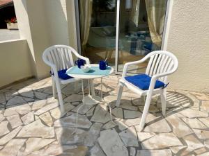 two white chairs and a table on a patio at Le temps des Pins in La Teste-de-Buch