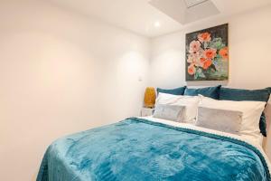 a bedroom with a blue bed with a painting on the wall at SkylightAnnex in Gaywood