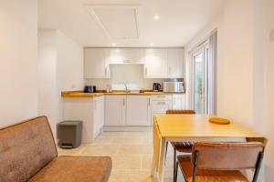 a kitchen with white cabinets and a wooden table at SkylightAnnex in Gaywood