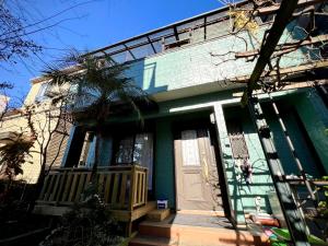 a green house with a porch and a door at Kenki Kawaguchi House 2-3F Guest Only 1F Occupied-ST0172 in Kawaguchi