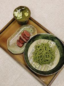 a tray with a plate of green pasta and meat at 光沙の森 in Hakone
