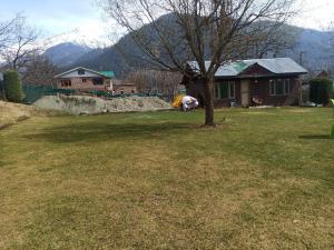 a yard with a house and a tree in the yard at Golf view resort in Pahalgām