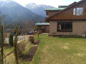 a house with a grass yard next to a building at Golf view resort in Pahalgām
