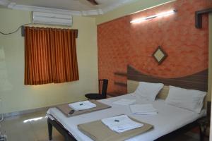 a bedroom with a bed with two towels on it at Hotel Sai Vishwa in Shirdi