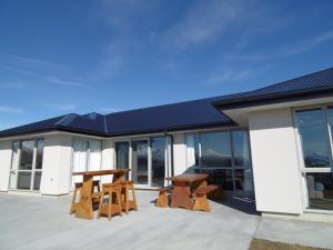 a building with two tables and benches on a patio at Southholm in Lake Tekapo