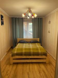 a bedroom with a bed and a window and a chandelier at Pstrug House in Yasinya +15 photos
