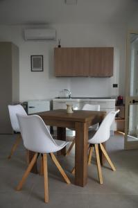 a kitchen with a wooden table and white chairs at Villa Catalano in Paola