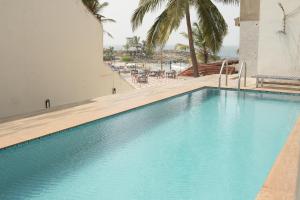 a swimming pool next to a beach with palm trees at Hotel Searock in Trivandrum